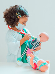 A little girl playing the doctor gives her patient an injection, they all wear protective masks