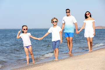 Happy family walking on sandy beach near sea. Summer holidays