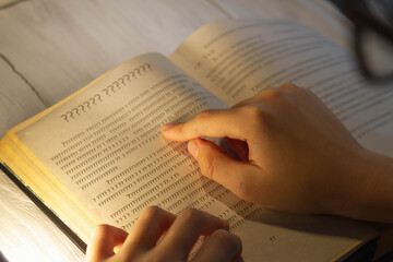 A person tries to read the text in a book, but sees only unknown words and letters.