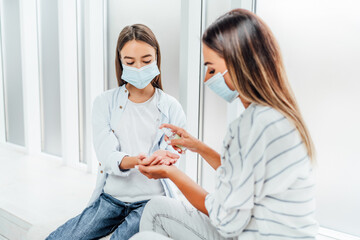Hand disinfection. A mother disinfects her child's hands after the street