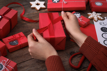 Woman decorating gift box at wooden table, closeup. Creating advent calendar