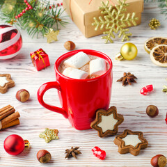 Obraz na płótnie Canvas Winter drink with marshmallows in red cup on wooden background with cookies and christmas decoration.