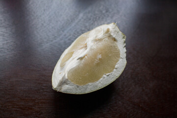 a piece of pomelo fruit on a dark kitchen table