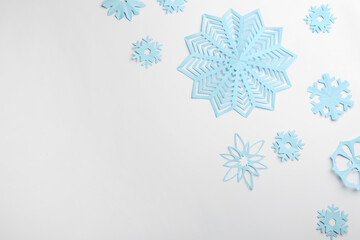 Fototapeta premium Many paper snowflakes on white background, flat lay. Space for text