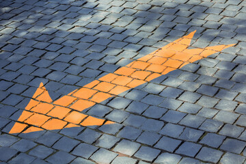 Directional sign drawn on cobbled road for cars.