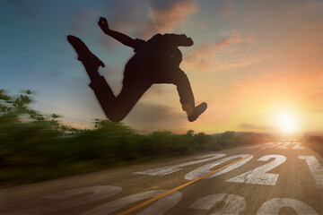 Silhouette man run and jump from 2020 to 2021 year on straight road to sunset. New year challenge...