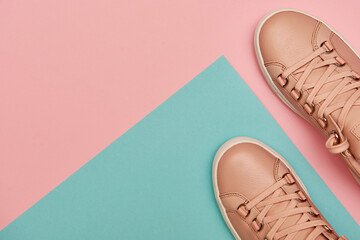 Stylish pink female shoes on pastel background, copy space. New sneakers on pink and blue background. Beauty and fashion concept. Flat lay, top view. Overhead shot