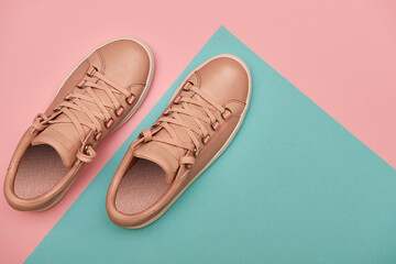 Stylish pink female shoes on pastel background, copy space. New sneakers on pink and blue background. Beauty and fashion concept. Flat lay, top view. Overhead shot