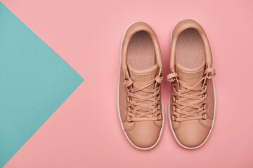 Stylish pink female shoes on pastel background, copy space. New sneakers on pink and blue background. Beauty and fashion concept. Flat lay, top view. Overhead shot