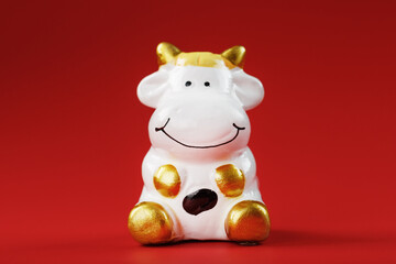 Christmas toy of a cow made of ceramic on a red background. 2021 year of the Bull, cow. New year's symbol
