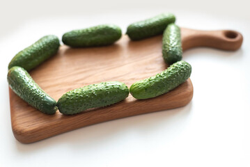 Creative layout of fresh vegetables cucumbers on wooden board on white