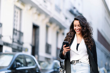 Fototapeta premium Beautiful woman using a mobile in the street. Communication concept