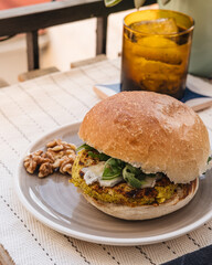 Chickpeas veggie burger on a table with a tonic water glass.