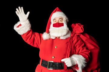 Santa Claus in a beautiful mask greets with a raised hand. Black background.