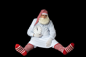 Santa Claus in a nightgown sits on the floor and regrets that he was late for Christmas. On a black background.