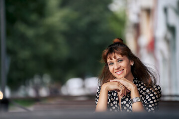 Naklejka premium Smiling woman in a summer city cafe. copy space.
