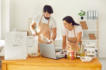 Employees of a restaurant form an order for an online delivery service and pack it in packages.