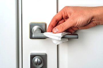 Naklejka premium Hand wipes the door handle with an antibacterial disinfecting cloth, prevention of coronavirus