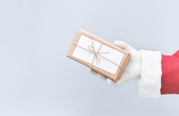 santa's hand holding a christmas gift wrapped in craft paper. zero waste christmas. eco and sustainable presents. hand made wrapping. copy space. crop view