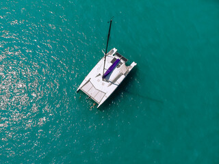 Picturesque top view of a huge white catamaran sailing across the deep sea. Aerial view.