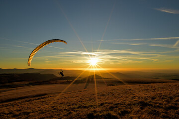 Ein Paraglider fliegt in den Sonnenuntergang 