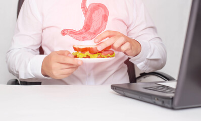 A male office worker holds a sandwich in his hands during lunch. The concept of unhealthy food, snacking, stomach pain. Gastritis and heartburn