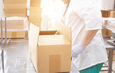 A worker controls the weight and quality of products in a box in a food production, background,...