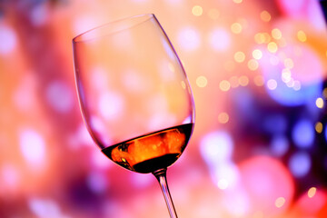Glass with rose wine against a colorful festive background. The mood of the holiday, happiness and fun.
