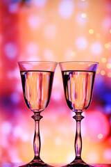 Two glasses with sparkling wine on a colorful festive background. The mood of celebration, happiness and fun.