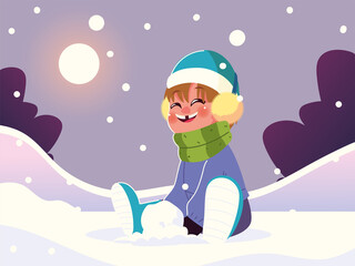 happy boy with warm clothes sitting in snow playing