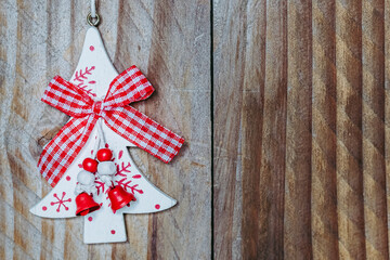 Décoration de Noël en forme de sapin avec noeud et ornements rouge et blanc sur un fond en bois...