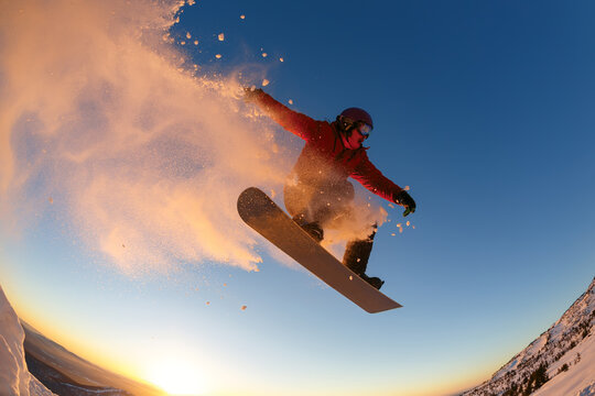 Snowboarder jumping against the sunset sky