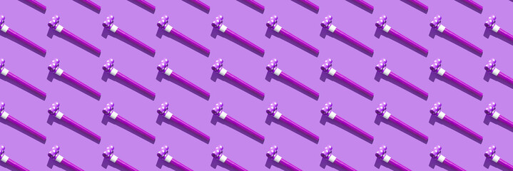 Obraz premium Festive air whistles on violet background. Pattern from elements of Christmas party with hard shadow. Christmas and New Year composition background for holidays. Flat lay. Top view.