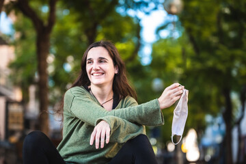 Young woman removes mask from her face with relief before the end of the pandemic