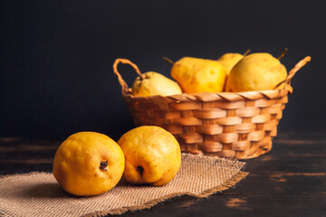 Natural pear fruit with defects in a basket on a jute napkin and a dark wooden background