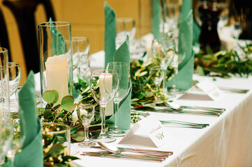 Elegant table setting at the restaurant. Wedding banquet with floral decoration on table, cards, glasses and cutlery closeup