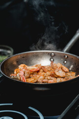 Shrimp on frying pan. Thermal processing of food. Electric cooker in a restaurant