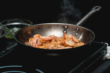 Shrimp on frying pan. Thermal processing of food. Electric cooker in a restaurant