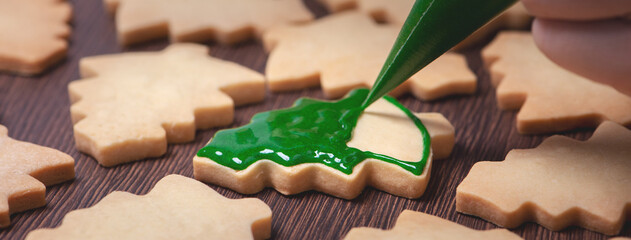 Close up of drawing Christmas tree sugar cookie on wooden table background with icing.