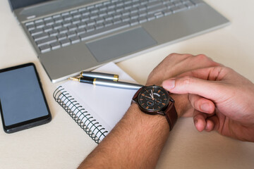 man's hands adjusting the schedule on watch, while working in the office.