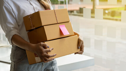 A young Asian woman shopping online starts a small business in a cardboard box at work. Seller provides shipping boxes for online sales customers.