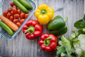 Fresh and colorful bell peppers and other vegetables on wooden table