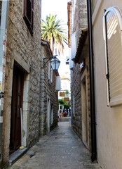 Narrow street in the old medieval town of Budva with Venetian Mediterranean architecture. Windows with shutters and shutters, street masonry