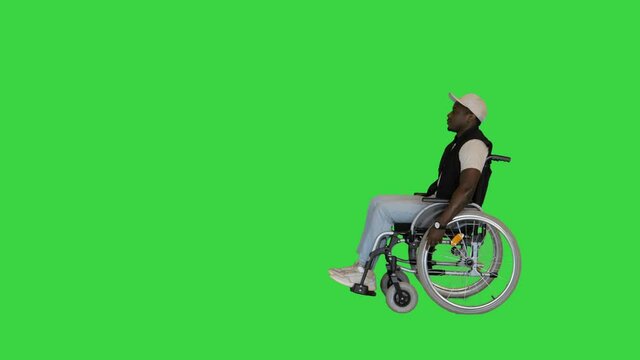 African disabled man sitting in wheelchair driving by on a Green Screen, Chroma Key.