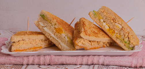 Cuatro sandwich mixtos uno encima de otro sobre una fuente blanca