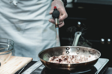 The chef cooks the small octopus on a metal frying pan