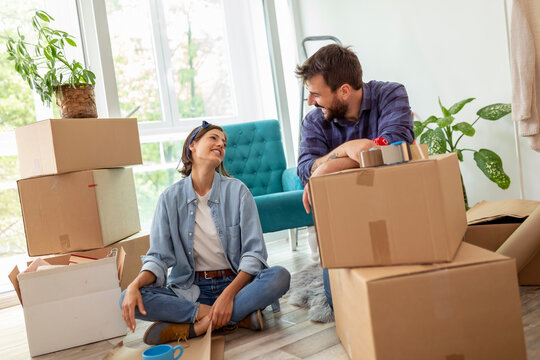 Couple paking things in cardboard boxes while moving house