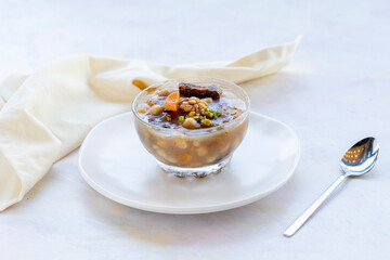 Traditional Turkish Dessert Aşure or Noah's Pudding with ingredients on white in stylish bowl: Aşure 
