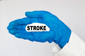 The doctor's blue - gloved hands show the word STROKE - . a gloved hand on a white background. Medical concept. the medicine