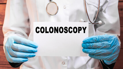 The doctor's blue - gloved hands show the word COLONOSCOPY - . a gloved hand on a white background. Medical concept. the medicine